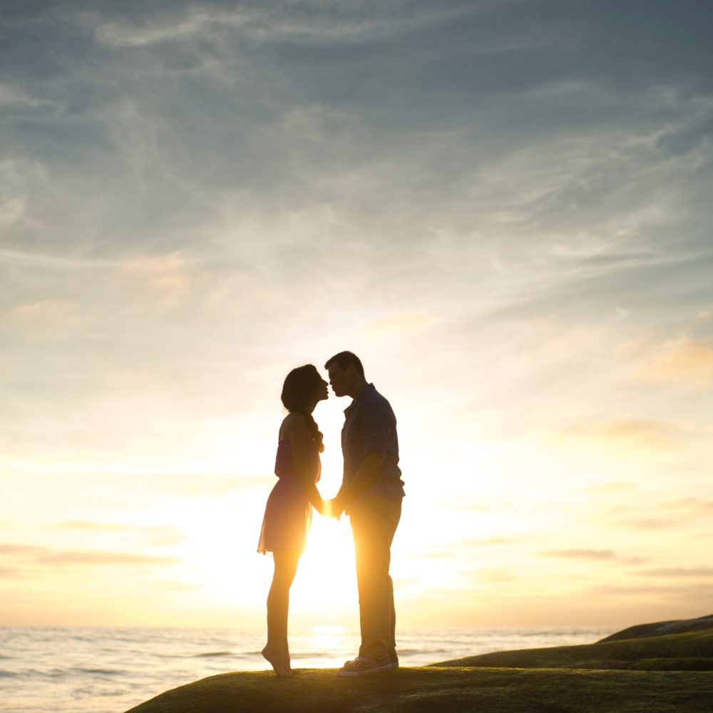 two people in kissing at sunset