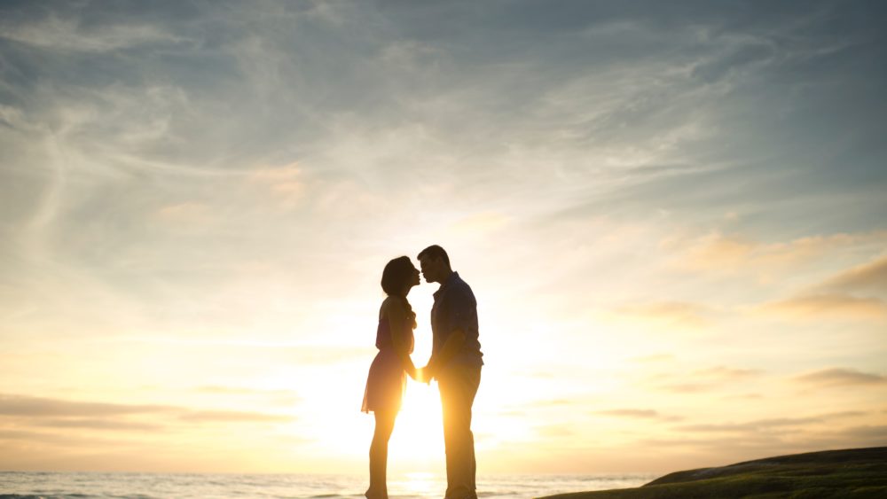 two people in kissing at sunset